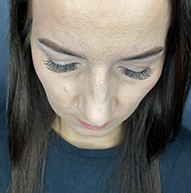 A woman with long brown hair, showcasing her eyelash extensions for a glamorous look.